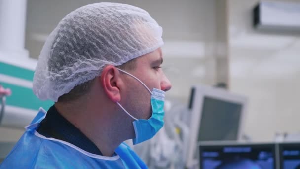 Widok Boku Twarzy Lekarza Masce Mężczyzna Chirurg Patrząc Monitor Podczas — Wideo stockowe