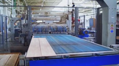 Kapalı alandaki modern fabrika. Robot ekipmanları ahşap parke tahtalar yapıyor. Modern fabrikada üretilen lamba paneller.