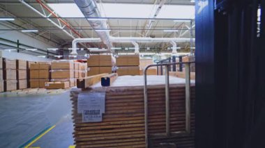 Parke deposunun içi. Tahta tahta taşıyan bir forklift. Fabrikanın içindeki plastik paneller yığını. Mobilya üretimi.