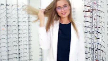 Genç bir kadın yeni gözlüğünü optikte kontrol ediyor. Gözlük takan ve kameraya poz veren güzel bir kız..