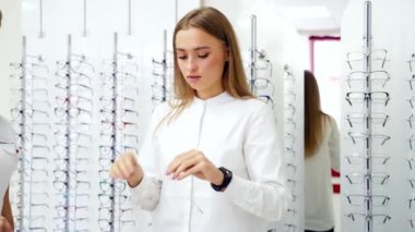 Gözlük dükkanı. Danışman, müşteriye bardak seçmesinde yardımcı oluyor. Güzel bir kadın yeni gözlük deniyor. Yaşam tarzı ve sağlık hizmeti kavramı.