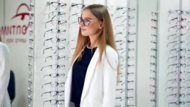 Mağazada yeni gözlüklü genç bir kadın. Modaya uygun gözlük seçen bir kız. Kadın optikte şık gözlük deniyor..