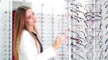 Optik mağazasında gözlük seçen hoş bir kadın. Güzel kız yeni gözlük alıyor. Görme ve sağlık konsepti.