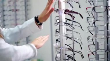 Görme konsepti. Optik mağazasında şık gözlüklü bir kadın var. Alıcı dükkanda yeni gözlük seçiyor..