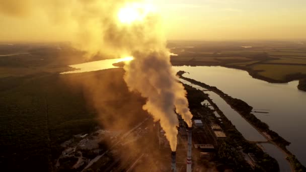 川の近くにある工場 日没時にパイプから空中に吸い込まれる厚い煙のトップビュー 自然の中で製造する エアリアルビュー — ストック動画
