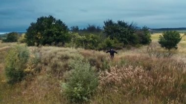 Tarladaki korkunç ölüm figürü. Siyah pelerinli hayalet, doğanın arka planında tek başına kollarını açmış duruyor..