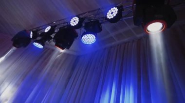 Renkli projektörler bir müzik çiftliğinde asılı. Konser salonunda ışıklar dönüyor ve parıldıyor. Gece kulübünde otomatik ışıklandırma teknolojisi.