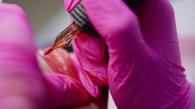 Dudaklarda kalıcı makyaj malzemesi. Kozmetoloji prosedürü. Elleri pembe eldivenli, kızın dudaklarında kalıcı kırmızı dövme var. Yakın plan..