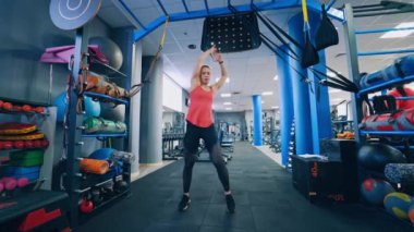Kapalı alanda bir sporcunun ön görüntüsü. Sportif kız vücudunu spor salonunda çalıştırıyor. Spor kulübü geçmişi üzerine egzersiz yapan bir kız..