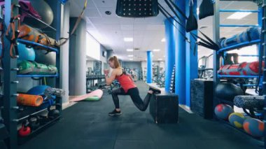 Spor salonunda çömelmiş bir kadın. Spor giyimli bir kız modern fitness merkezinde engelli duruyor. Sporcu kadın içeride antrenman yapıyor. Yan görünüm.