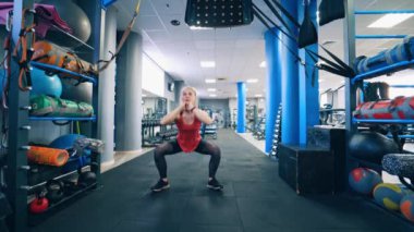Genç bayan spor salonunda çömeliyor. Çekici kız spor salonunda günlük egzersizini yapıyor. Sağlıklı yaşam tarzı.
