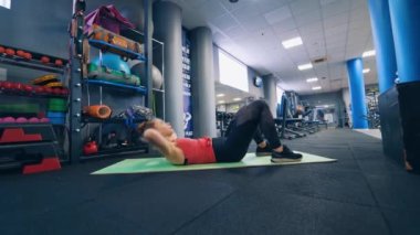 Karın egzersizi yapan kadının yan görüntüleri. Spor kıyafetli bir kadın paspasın üstünde spor yapıyor..