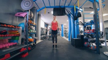 Spor salonuna atlayan güzel kız. Sportif genç bir kadın spor salonunda atlama halatıyla atlıyor..