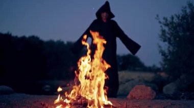 Karanlıkta ateş ve siyah figür. Pelerinli, parlak alevlere karşı duran ve açık havada ayin yapan ürkütücü bir ölüm. Cadılar Bayramı.