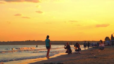 Deniz kıyısında fotoğraf çeken genç kadınlar. Deniz suyunun üzerinde güzel bir gün batımı ve akşamları fotoğraf çeken insanlar..