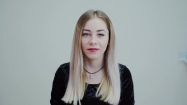 Parlak dudaklı sarışın bir kadının portresi. Stüdyoda yalnız başına kameraya bakıp gülümseyen güzel kız..