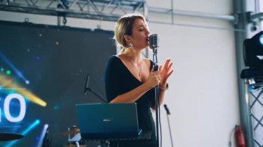 Kadın şarkıcı mikrofona müzik çalar. Müzikholde sahnede şarkı söyleyen profesyonel bir vokalist..