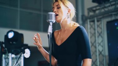 Sahnede müzik yıldızı. Çekici kadın şarkıcı özel etkinlik için mikrofona canlı müzik çalıyor. Yavaş çekim.