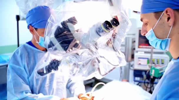 手術の最新機器 医療マスクの2人の専門医が顕微鏡を介して手術を行います — ストック動画
