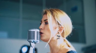 Genç profesyonel bayan şarkıcının yan görüntüsü. Sahnede mikrofona şarkı söyleyen güzel bir kızın yüzü. Müzik konseri.
