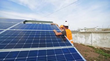 Yazın güneş pillerinin kurulumu. İşçiler fotovoltaik güneş paneli kuruyor. Temiz elektrik enerjisi elde etmenin yenilikçi teknolojileri.