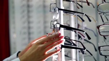 Optik mağazasında bayan müşteri. Kadının elleri kürsüden yeni bir gözlük alıyor. Yakın plan. Görüş konsepti.