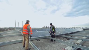 Elektrikte yenilikçi ekipman. Koruyucu üniformalı işçiler çatıya yeni güneş panelleri kuruyor. Güneşten yenilenebilir enerji.