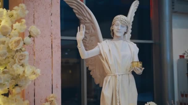 Белая Статуя Ангела Живая Статуя Женщины Крыльями Рядом Нежными Цветами — стоковое видео