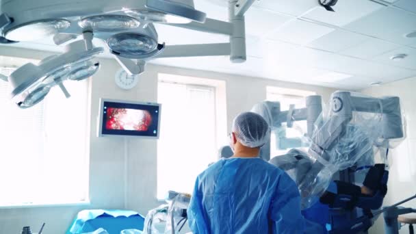 近代的な手術室での手術プロセス ロボット機器が動作する 医師は手術中にモニターの画面を見る — ストック動画