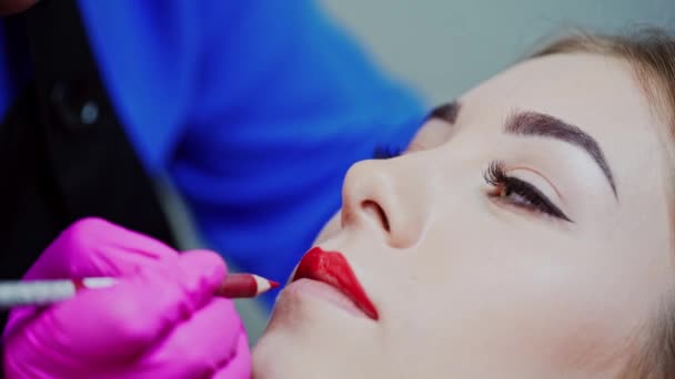 美容室で美しい女性の顔 常設メイクの前に赤鉛筆でクライアントの唇を描く化粧品 クローズアップ — ストック動画
