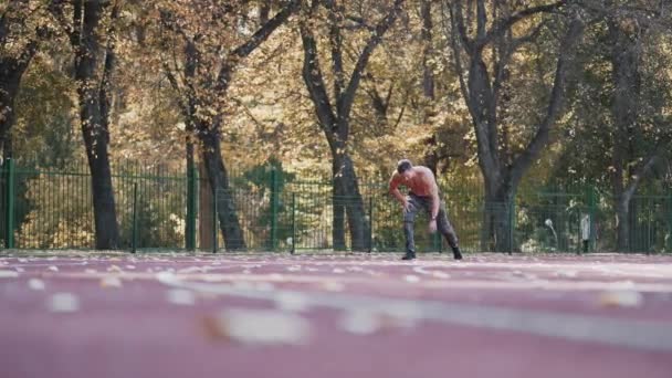 肌肉男正在室外体育场训练 没有衬衫的年轻运动员在田径运动跑道上跑步 健康的生活方式 — 图库视频影像