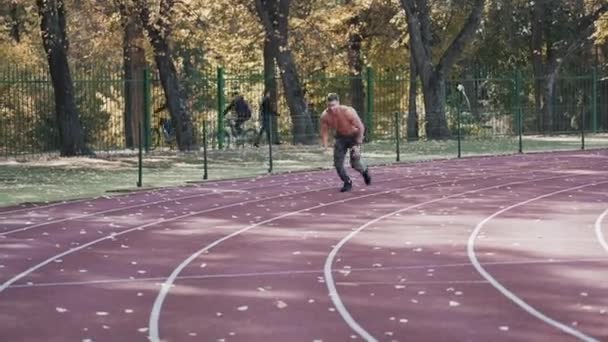 Młodzieniec Biegający Stadionie Sportowym Bezkoszulowy Sportowiec Biegający Jesienią Torze Lekkoatletycznym — Wideo stockowe