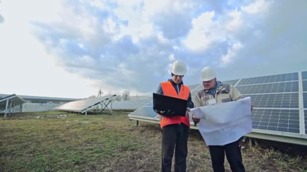 Teknisyenler Güneş Çiftliğindeki Dizüstü Bilgisayarlara Proje Planlarına Bakıyorlar Güneş Panellerinin — Stok video