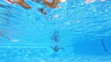 Suyun altında yüzen yakışıklı adam. Güneşli bir günde havuza atlamak. Yavaş çekim
