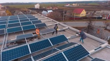 Binanın tepesine güneş panelleri kurulmuş. İşçiler çatıya yeni güneş pili taktılar. Güneşten yenilenebilir enerji. Hava görünümü.