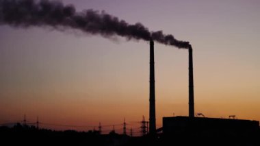 Akşam gökyüzündeki borulardan siyah duman. Endüstriyel fabrika borularından gelen kirli emisyonlar çevreyi kirletir. Ekolojik sorunlar.