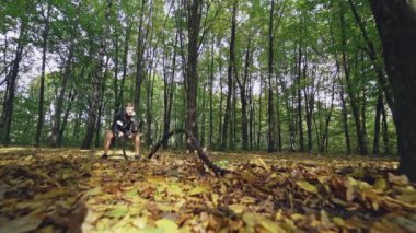 Sonbaharda ormanda savaş halatlarıyla antrenman yapmak. Sporcu dışarıda halatlarla dalgalar yapıyor. Ön manzara. Ağır çekim. Sağlıklı yaşam tarzı.