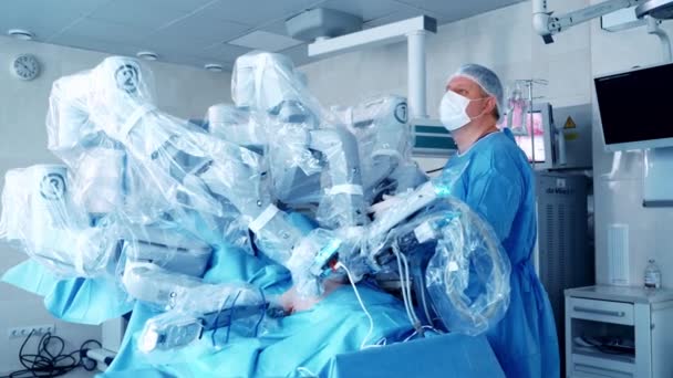 Robot Chirurgiczny Wykonuje Operację Chirurg Mundurze Medycznym Patrzący Ekran Podczas — Wideo stockowe