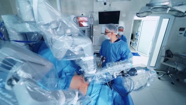 医学におけるハイテクロボットシステム 医療ロボットは クリニックの患者さんに手術を行います 労働者は外科ロボットの仕事を制御する — ストック動画
