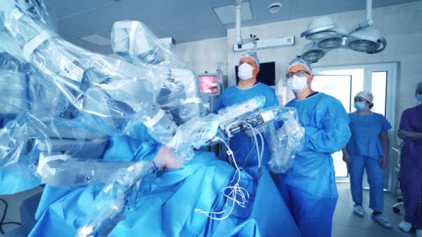 外科医のグループは ロボット操作を見ています オペレーティングルームの最新医療機器 最小侵襲ロボット手術 — ストック動画