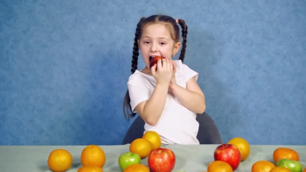 Niña Muerde Manzana Roja Sobre Fondo Azul Lindo Niño Comiendo — Vídeos de Stock