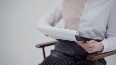 Kadının elindeki kağıtlarla klasör. Sandalyede oturan ve elinde belgeler tutan genç bir iş kadını. Yakın plan. Yavaş çekim.