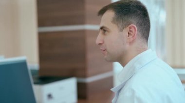 Klinikte omurga röntgeni tutan genç bir doktor. Modern ofisinde oturan ve birileriyle konuşan bir erkek uzman. Sağlık hizmetleri kavramı.