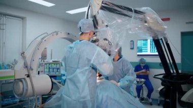 Modern ameliyathane. Hastanedeki bir hastaya mikroskopla iki doktor ameliyat yapıyor. Tıpta yeni ekipman.