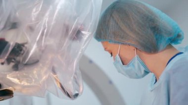 İşteki bir kadın doktorun portresi. Hastanedeki modern tıbbi ekipmanların yanında maske takan bir kadının yan görüntüsü..