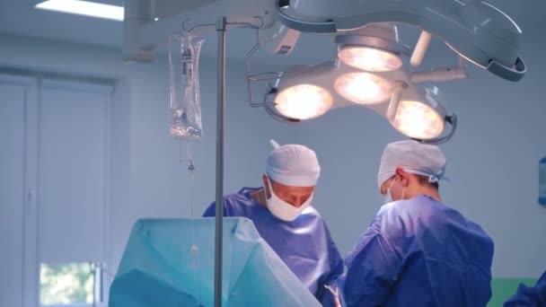 전문가와 현대적인 수술실 비서가있는 외과의사가 병원에서 아래에서 수술을합니다 — 비디오