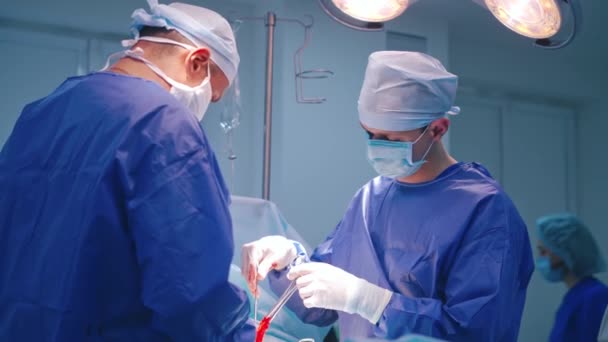 两名身穿蓝色军服的外科医生的档案 现代诊所操作过程中使用医疗器械的专家 — 图库视频影像