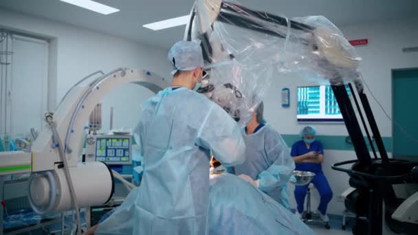 現代のオペレーティングルーム 2人の医師が病院の顕微鏡を通して患者に手術を行う 新しい医療機器 — ストック動画