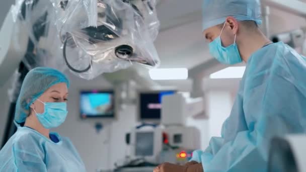 手術室のドクターとアシスタント 医療用ユニフォームのスペシャリストは 手術前に顕微鏡をカスタマイズします メディカルコンセプト — ストック動画