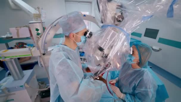 기기를 사용한 외과의사는 현미경을 수술을 수행합니다 조수는 진료소에서 의사를 돕습니다 — 비디오